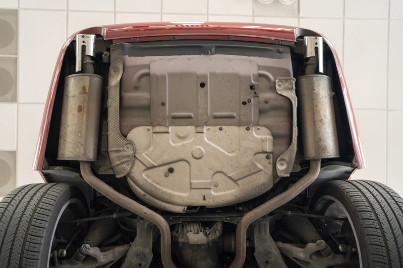 Underside view of a red 2006 Jaguar XJR showing dual exhaust and suspension components.