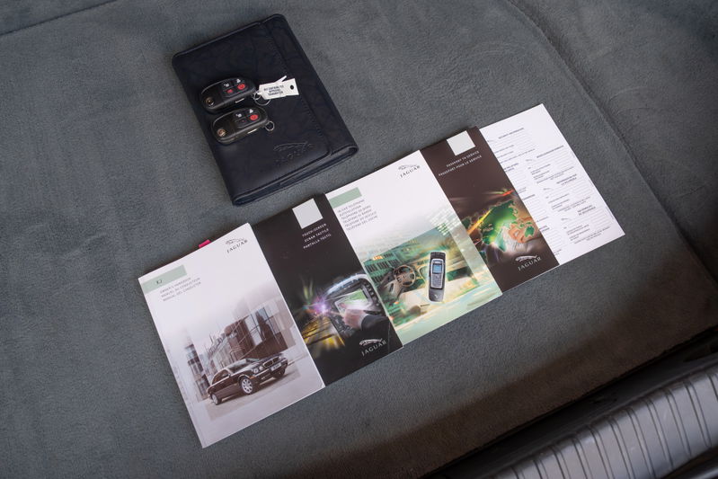 Jaguar XJR owner's manual, service book and keys on gray seat.