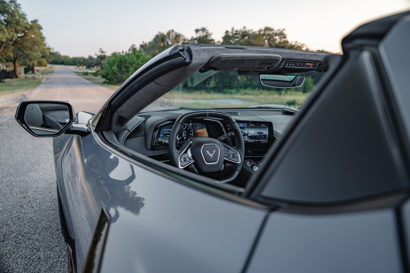Gray 2025 Chevrolet Corvette Z06 convertible interior and side mirror, parked on a road.