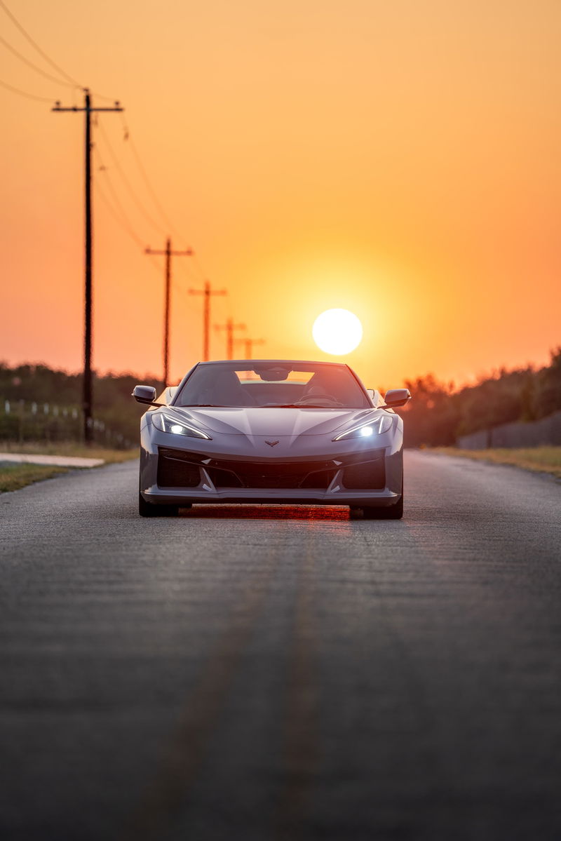 Front view of a Sea Wolf Gray 2025 Chevrolet Corvette Z06 on a road at sunset.