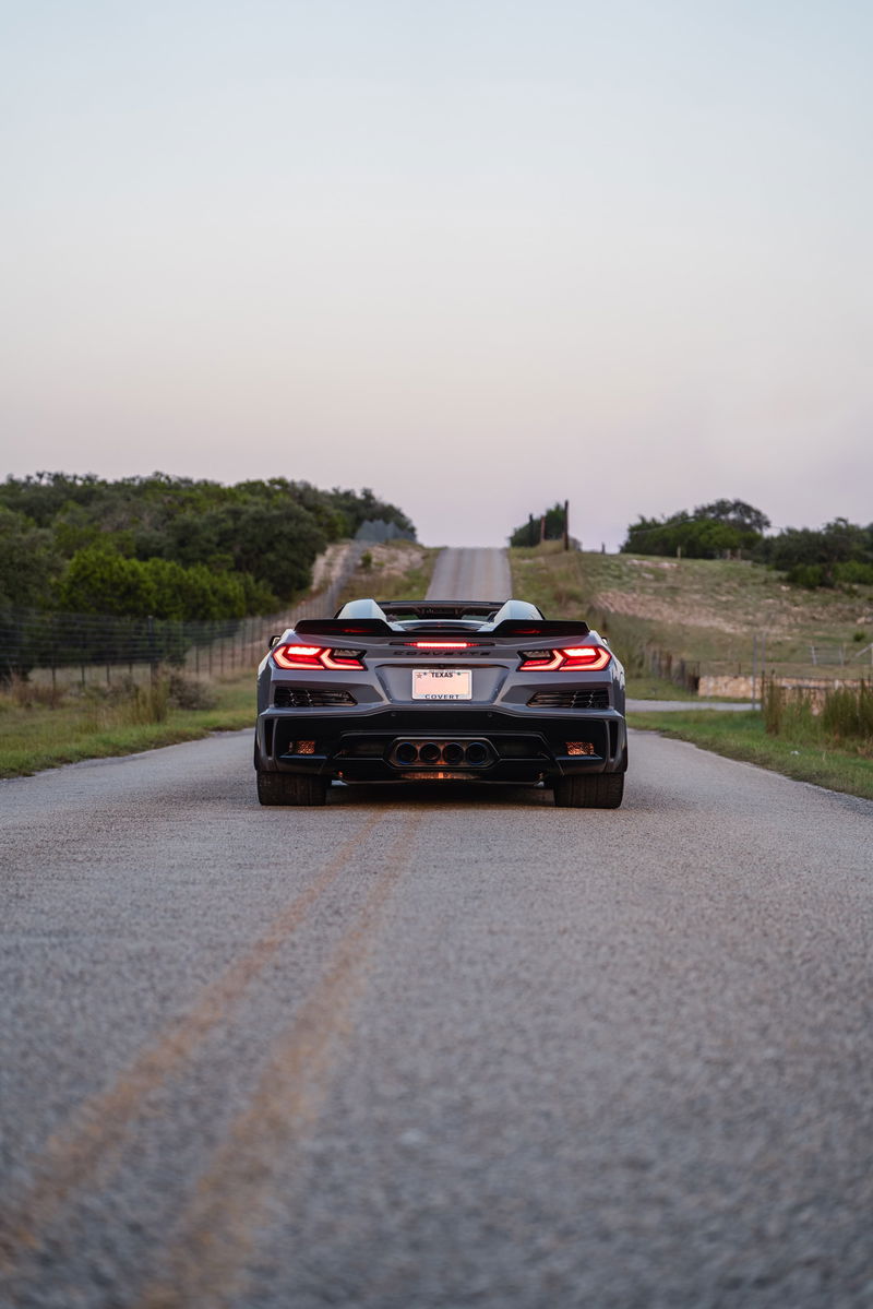 Rear view of a Sea Wolf Gray 2025 Chevrolet Corvette Z06 convertible on a rural road.