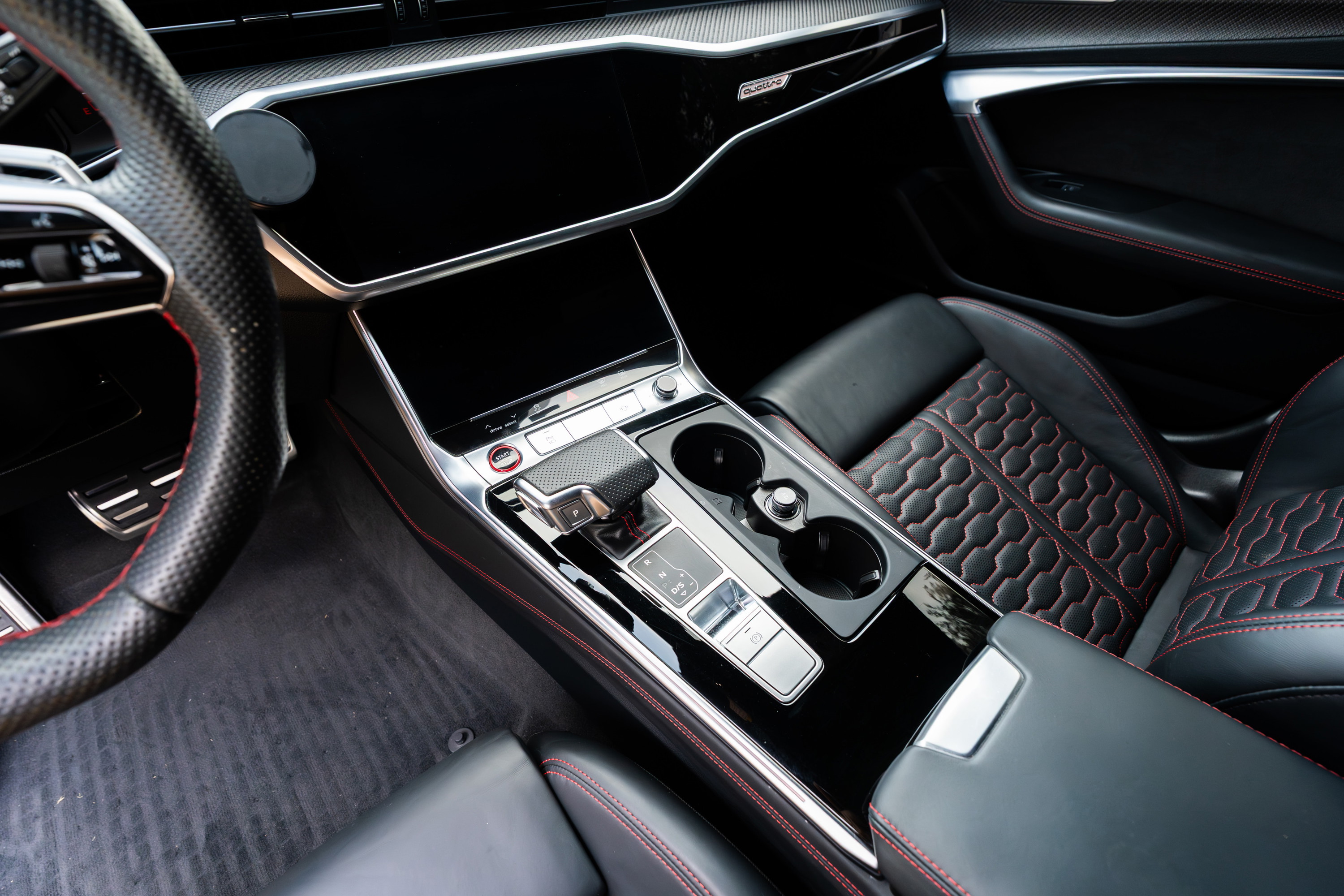 Interior shot of a 2022 Audi RS6 with Nardo Grey exterior, black leather, red stitching, and carbon fiber trim.