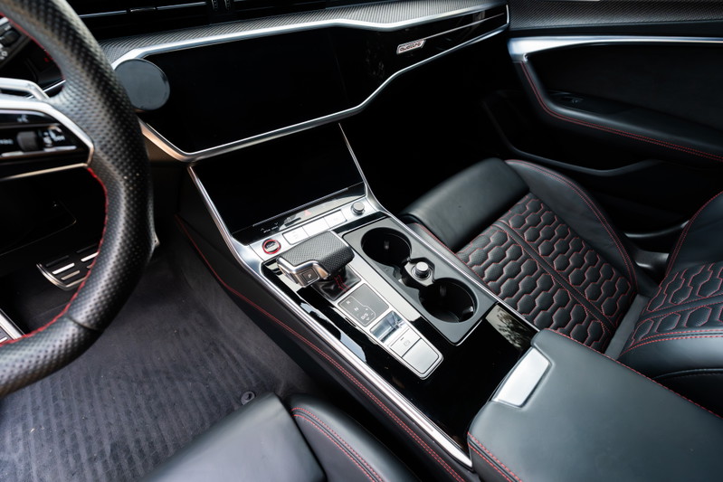 Interior shot of a 2022 Audi RS6 with Nardo Grey exterior, black leather, red stitching, and carbon fiber trim.