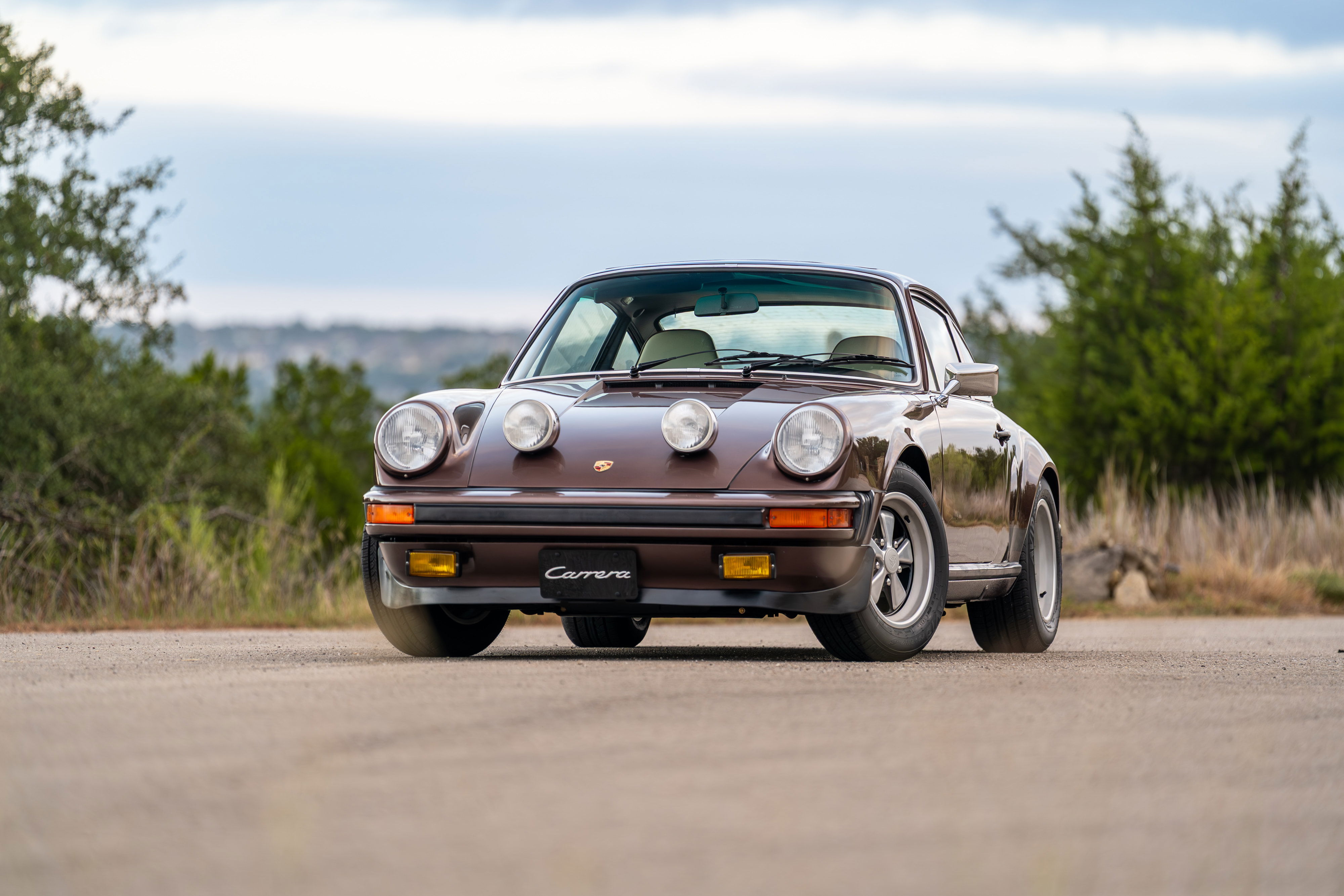 Copper brown metallic 1975 Porsche 911 Carrera with Fuchs rims and fog lights.