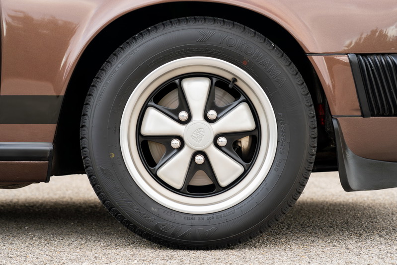 Close-up of a copper brown 1975 Porsche 911 Carrera with Fuchs wheels.