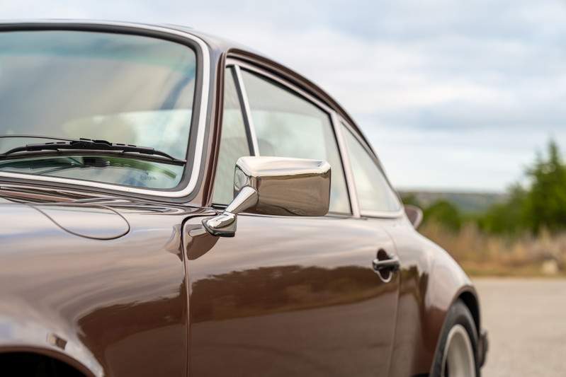 Brown metallic 1975 Porsche 911 Carrera detail shot, showing chrome trim and side mirror.