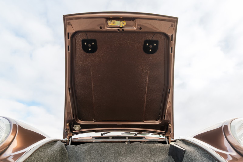 Open hood of a copper brown metallic 1975 Porsche 911 Carrera showing the front trunk lining.