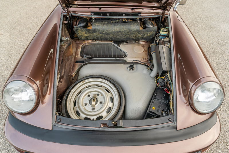 Copper brown metallic 1975 Porsche 911 Carrera's front trunk with spare wheel.