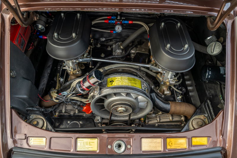 Close-up of a vintage copper brown metallic 1975 Porsche 911 Carrera engine bay. Twin Weber carburetors, fan shroud.