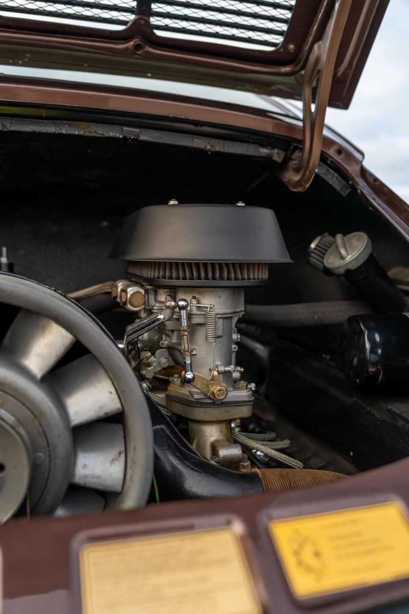 Detail shot of a 1975 Porsche 911 Carrera engine, showing a Weber carburetor and cooling fan.