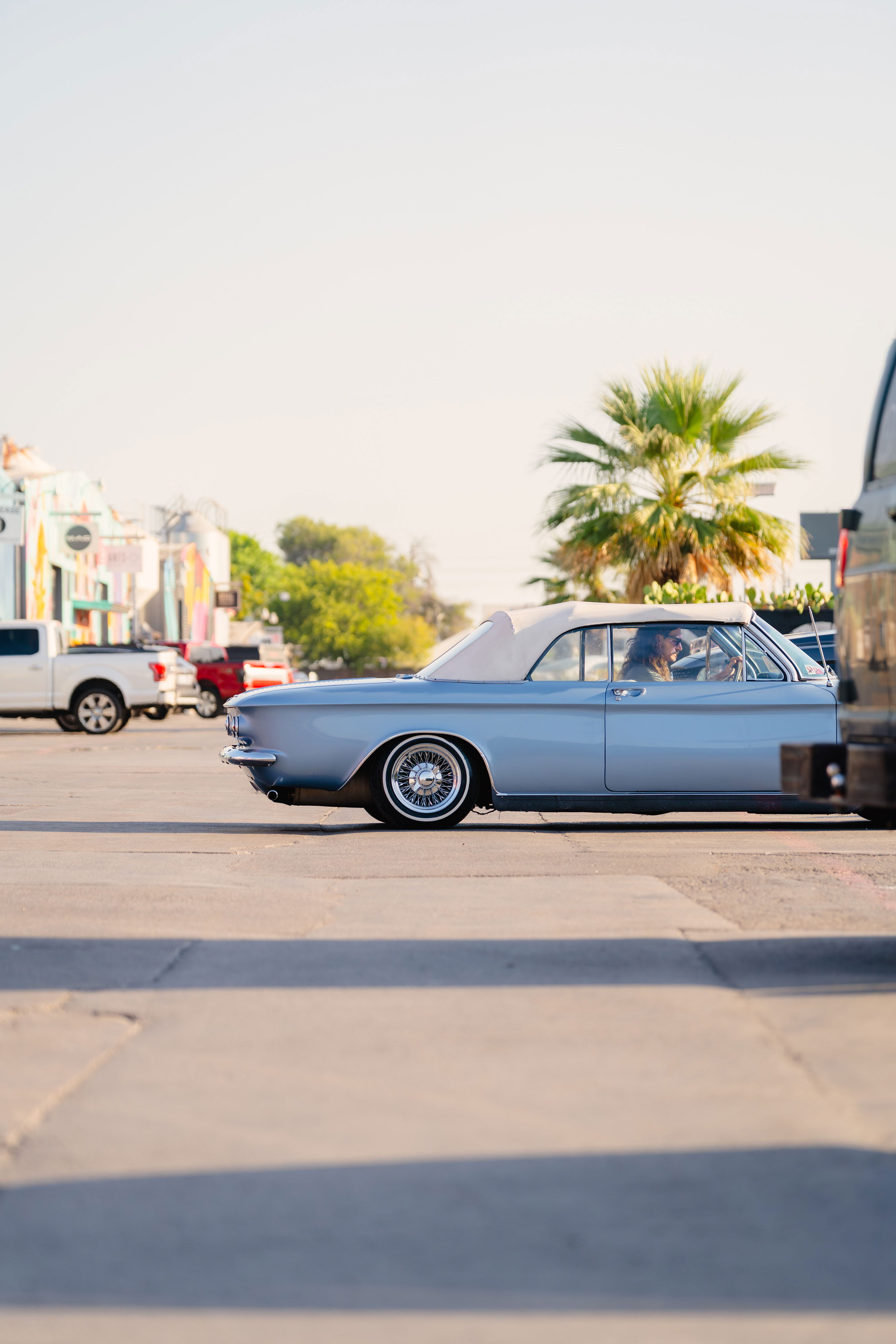 Side profile of a powder blue 1966 Chevrolet Corvair convertible with wire wheel rims.