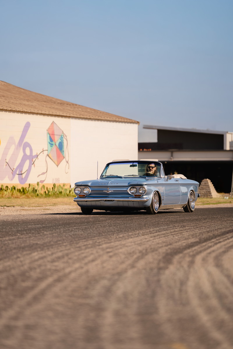1966 blue metallic Chevrolet Corvair convertible with chrome trim and whitewall tires.
