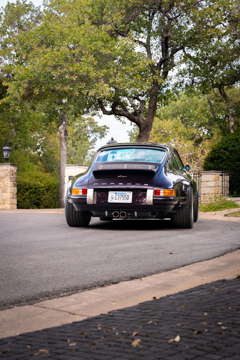 Aubergine metallic 1990 Singer Porsche 911 rear view, showing chrome exhaust tips and Fuchs rims.