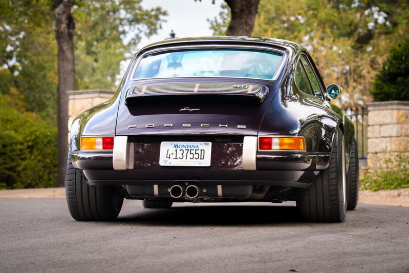 Rear view of an aubergine metallic 1990 Singer 911 with polished exhaust tips and wide wheels.
