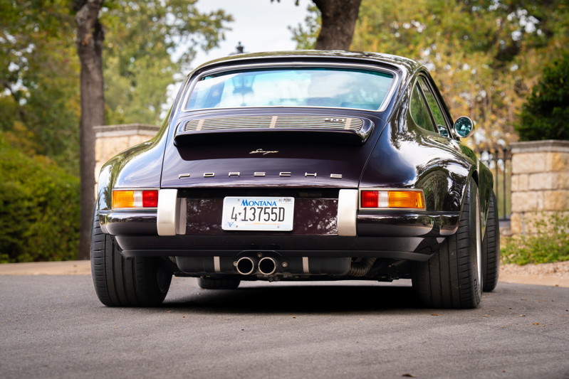 Rear view of an aubergine metallic 1990 Singer 911 with polished exhaust tips and wide wheels.