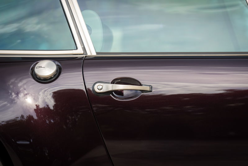 Aubergine metallic 1990 Singer 911 door with chrome trim, oil cap, and door handle.