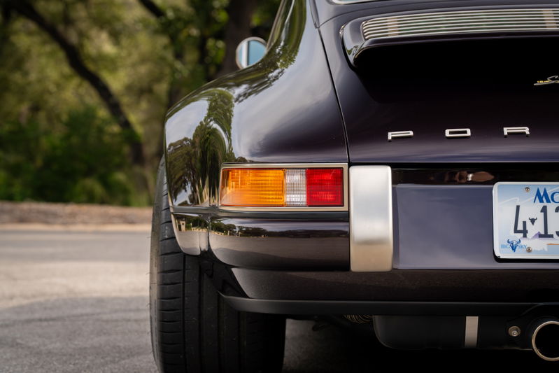 Close-up rear view of an aubergine metallic 1990 Singer Porsche 911, showing chrome trim and taillights.