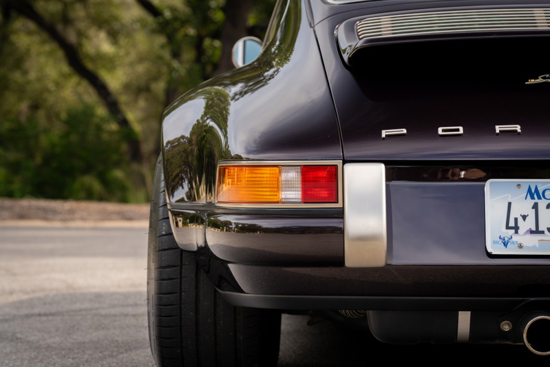 Close-up rear view of an aubergine metallic 1990 Singer Porsche 911, showing chrome trim and taillights.
