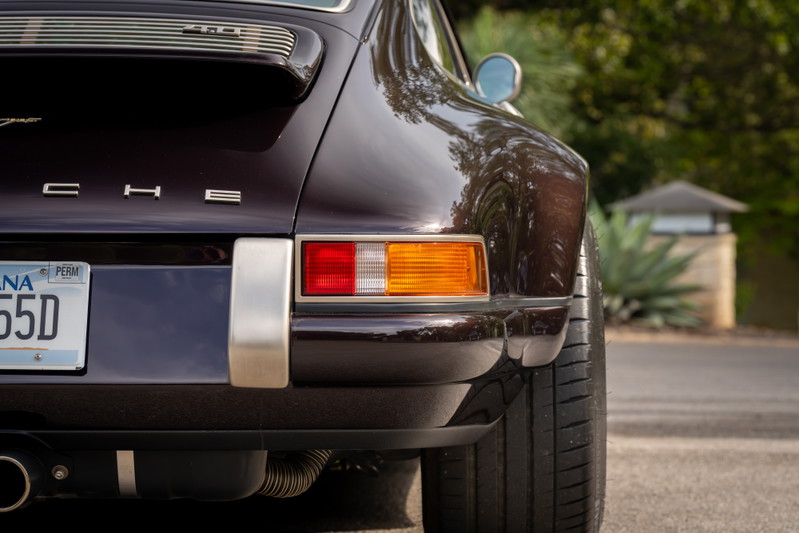 Aubergine metallic 1990 Singer Porsche 911, rear view, showing taillights, chrome trim, and exhaust.
