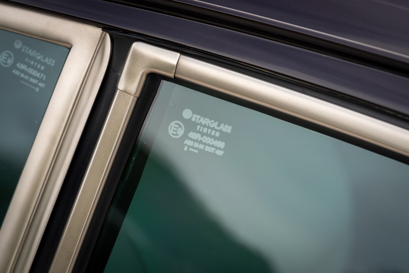 Close-up of a 1990 Singer Porsche 911's aubergine metallic door frame and tinted Starglass window.