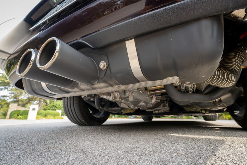 Dual chrome-tipped exhaust pipes on an aubergine metallic 1990 Singer Porsche 911.