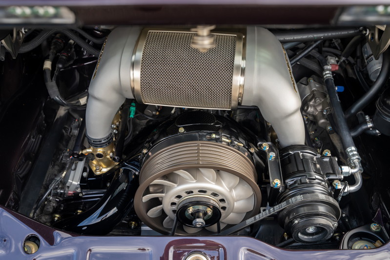 Aubergine metallic 1990 Singer 911 engine bay. Turbocharged flat-six engine with polished intake piping and mesh air filter.