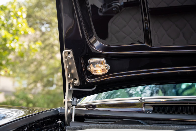 1990 Singer Porsche 911's hood light illuminates the aubergine metallic paint and polished hinge.