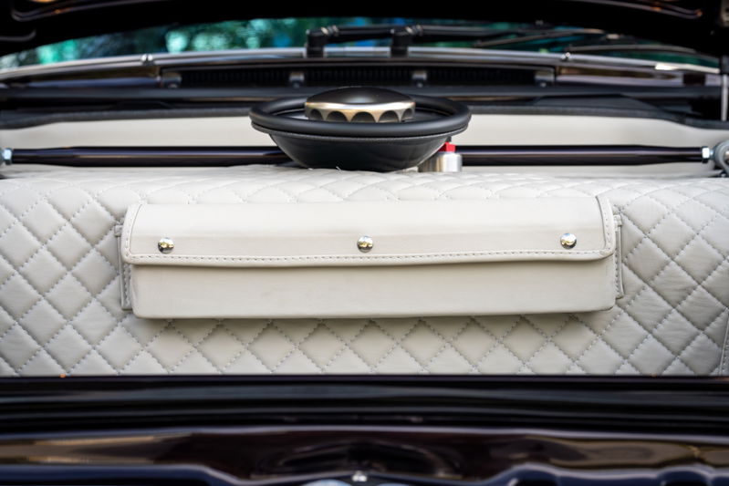Close-up of a quilted interior of a 1990 aubergine metallic Singer Porsche 911 with a leather storage pouch.