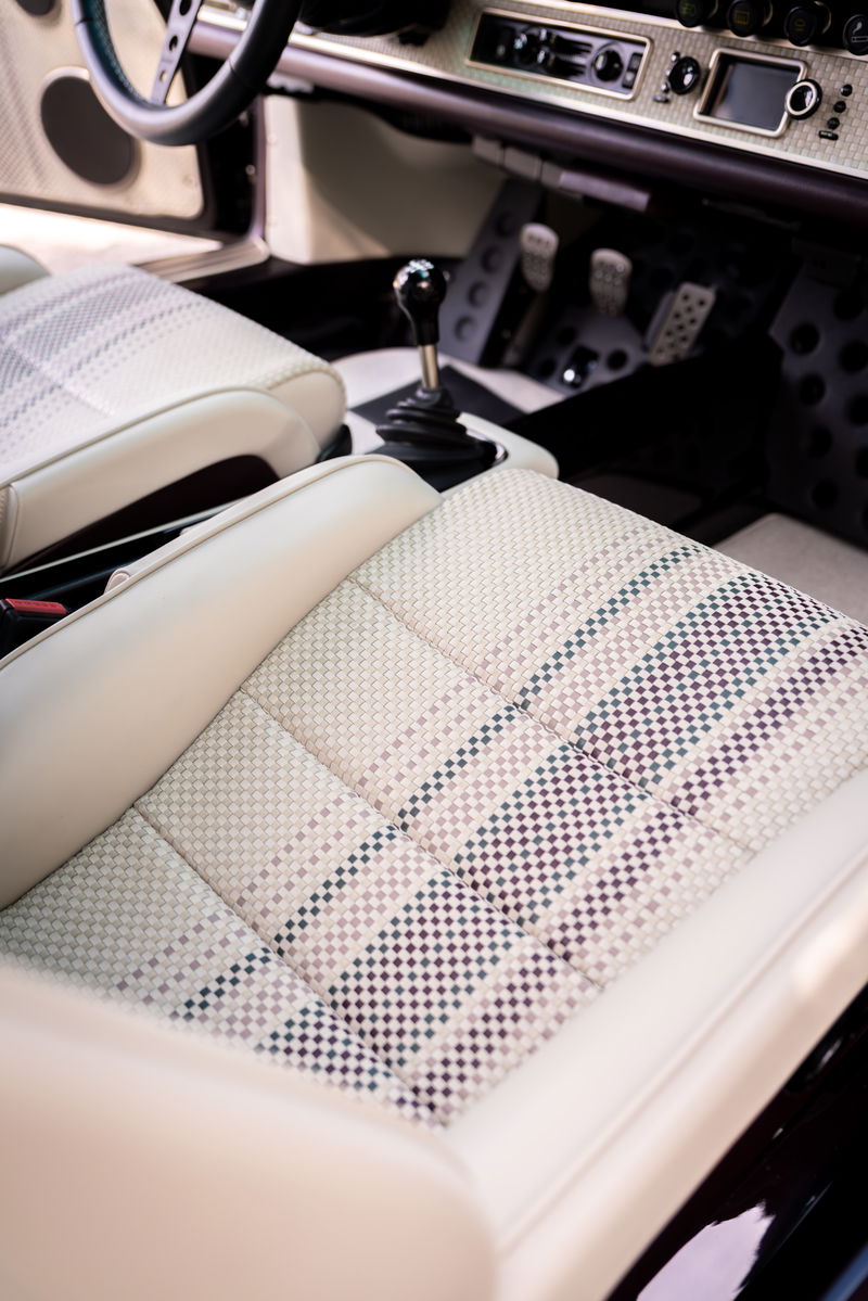 Interior of an Aubergine Metallic 1990 Singer Porsche 911, featuring tartan seat inserts and a gated shifter.