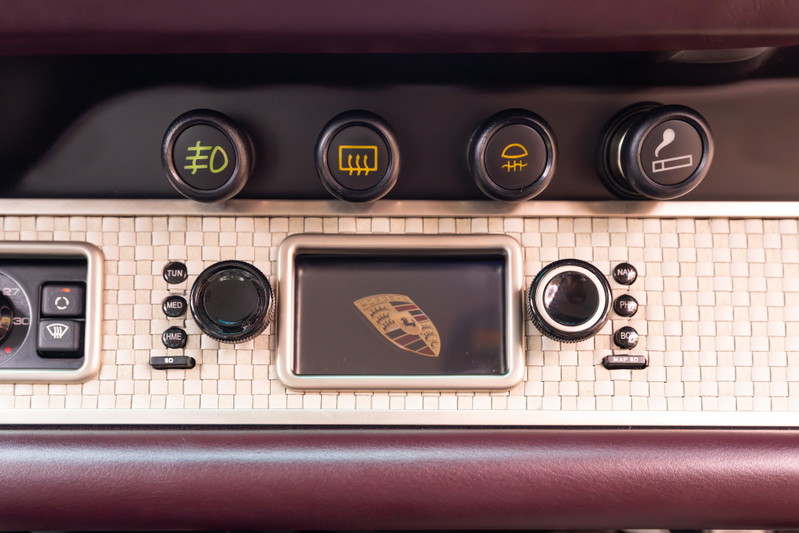 Close-up of the 1990 Singer Porsche 911 aubergine metallic dashboard trim with center screen.