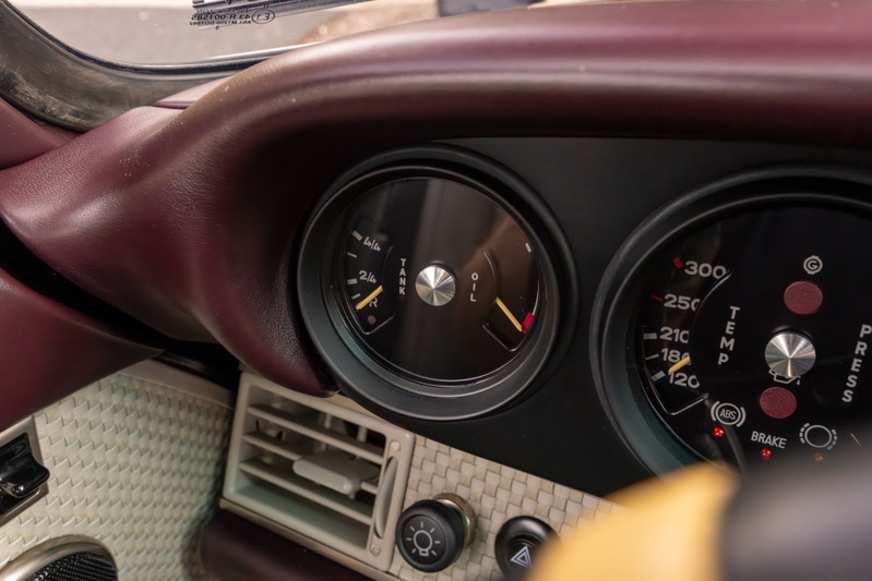 Singer 911 dashboard detail: aubergine metallic interior trim, oil temp gauge, and other classic gauges.