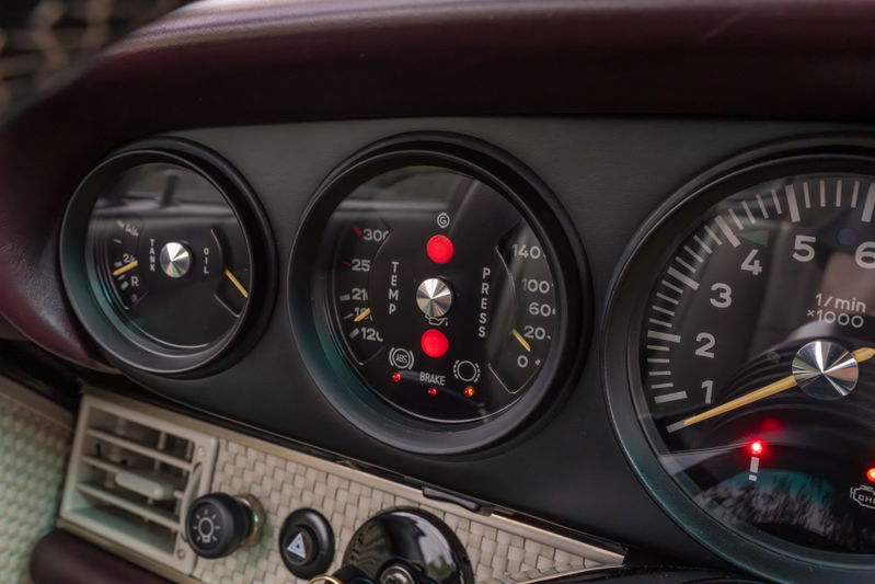 Close up of a 1990 Singer Porsche 911 dashboard with aubergine metallic interior trim.