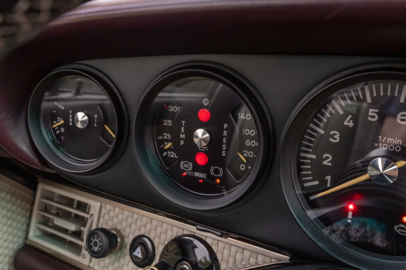 Close up of a 1990 Singer Porsche 911 dashboard with aubergine metallic interior trim.