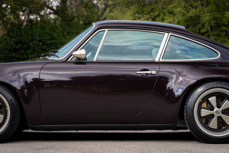 1990 Singer Porsche 911 coupe in Aubergine Metallic, side profile. Chrome trim and Fuchs-style rims visible.