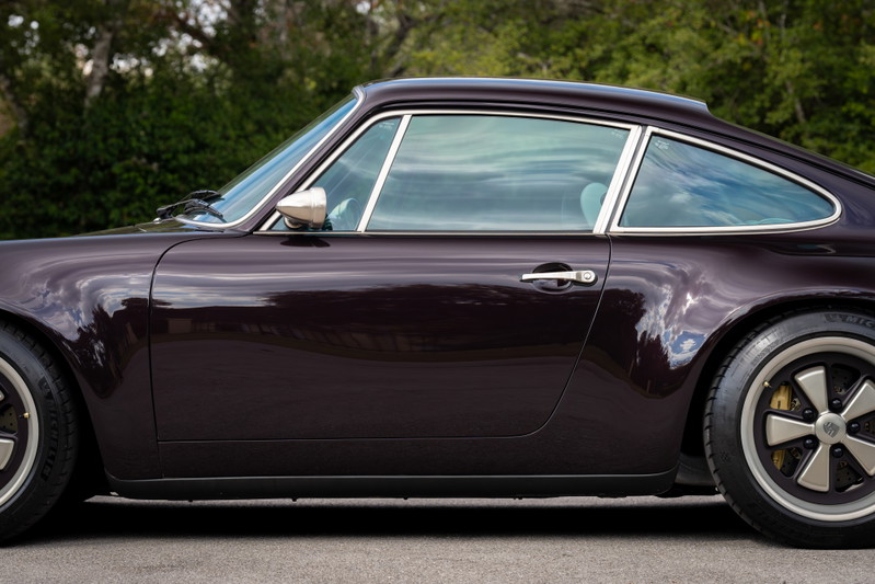 1990 Singer Porsche 911 coupe in Aubergine Metallic, side profile. Chrome trim and Fuchs-style rims visible.