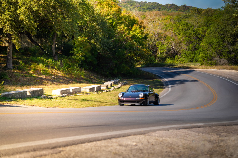 Aubergine Metallic 1990 Singer 911 on a winding road, showcasing its classic lines and subtle trim.