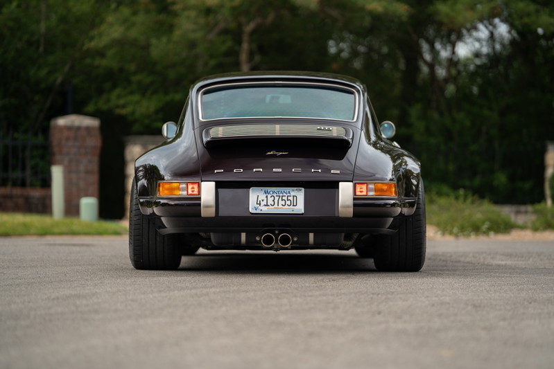 Aubergine metallic 1990 Singer Porsche 911 rear view with chrome trim and dual exhaust.