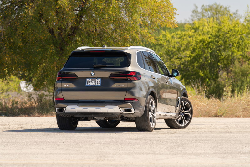 2026 BMW X5 in Manhattan Green, featuring black and silver multi-spoke rims and chrome exhaust tips.