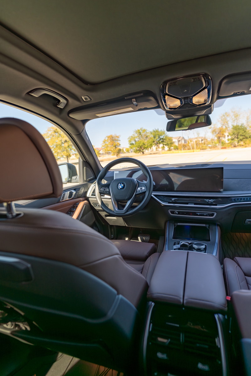 2026 BMW X5 interior with Manhattan Green exterior, featuring brown leather seats and a panoramic sunroof.