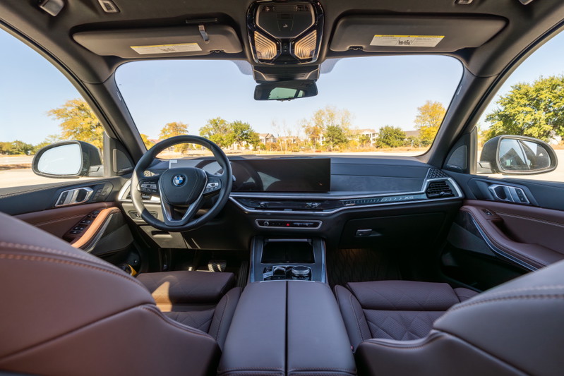 Interior view of a 2026 BMW X5 in Manhattan Green, featuring quilted brown leather trim.