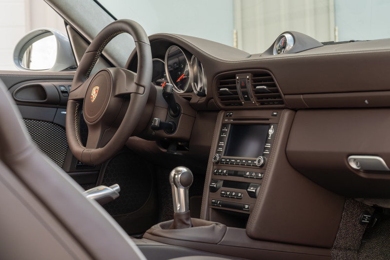 2010 Porsche 911 Sport Classic interior: brown leather trim, manual shifter, touchscreen.
