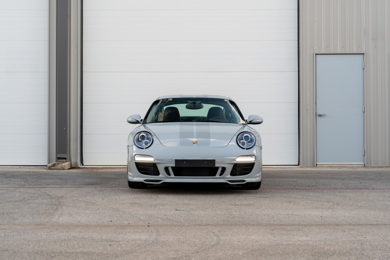 Front view of a grey 2010 Porsche 911 Sport Classic with racing stripes and silver rims.
