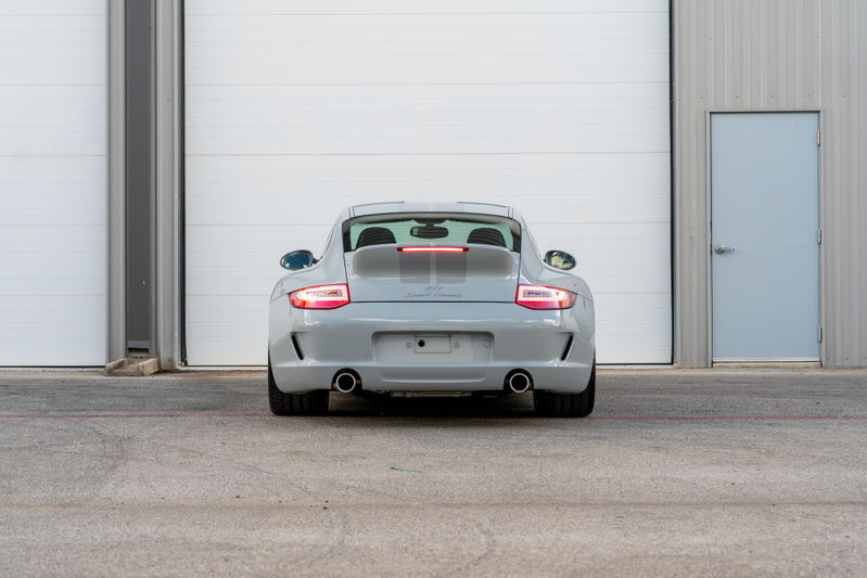 Rear view of a grey 2010 Porsche 911 Sport Classic with a prominent rear wing and dual exhaust tips.