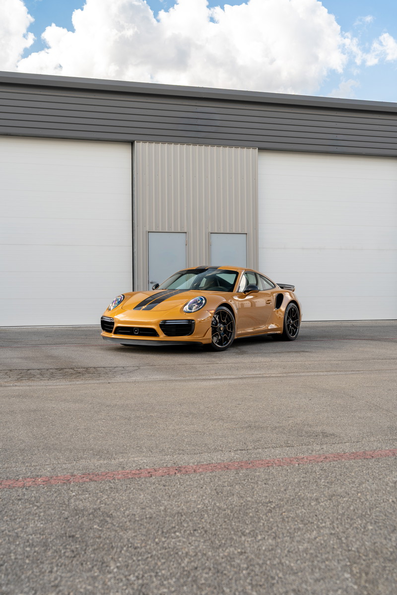 2018 Porsche 911 Turbo S Exclusive Series in Golden Orange Metallic with black racing stripes, black rims.