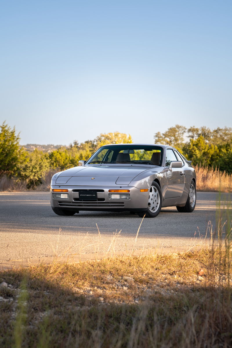 1987 silver Porsche 944 Turbo S coupe with Turbosport rims on a paved road.