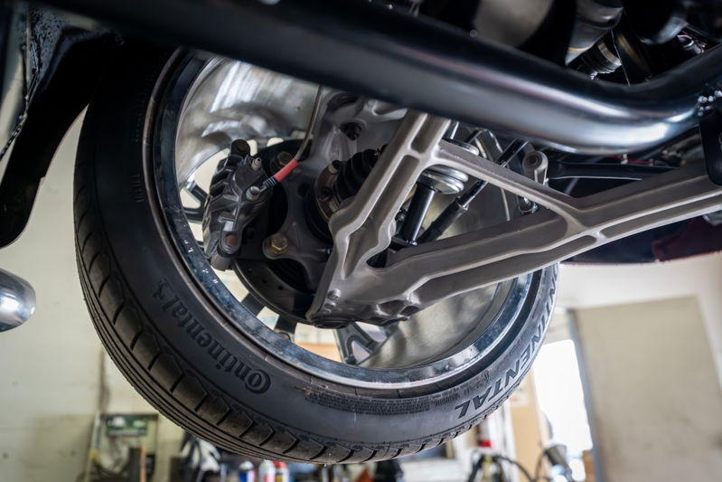Close-up of a 1965 Chevrolet Corvette's suspension, showing the wheel, brake caliper, and control arm.
