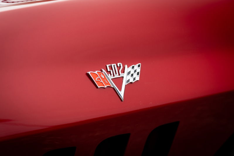 Red 1965 Corvette "502" emblem on shiny red paint.