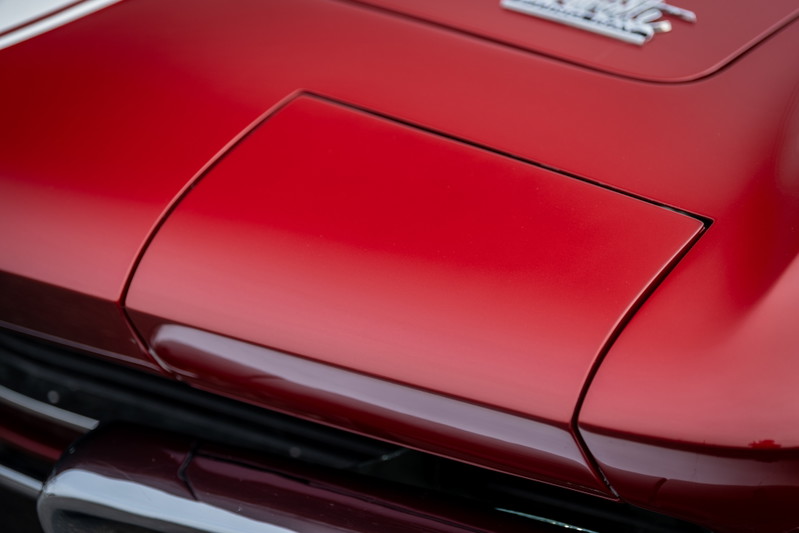 Red 1965 Chevrolet Corvette hood with chrome trim detail.