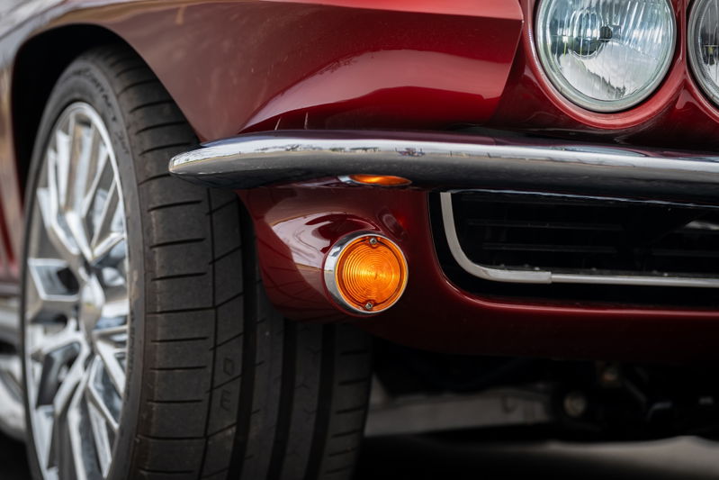 Red 1965 Chevrolet Corvette hot rod, close up of front fender, chrome bumper, and chrome rims.