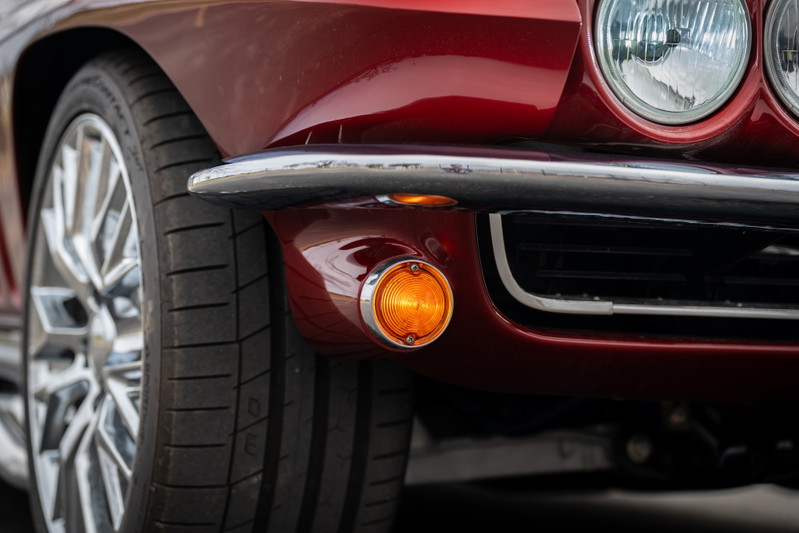 Red 1965 Chevrolet Corvette hot rod, close up of front fender, chrome bumper, and chrome rims.